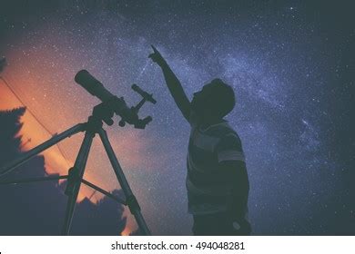 Man Looking At The Stars With Telescope Beside Him Stock Photo